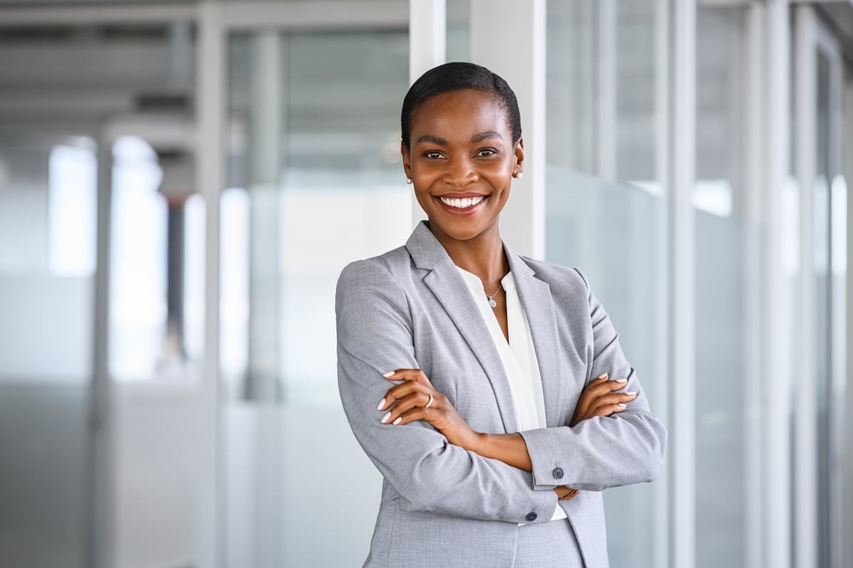 Portrait of mid adult successful black mature woman looking at camera with arms crossed, smiling, confident businesswoman in office